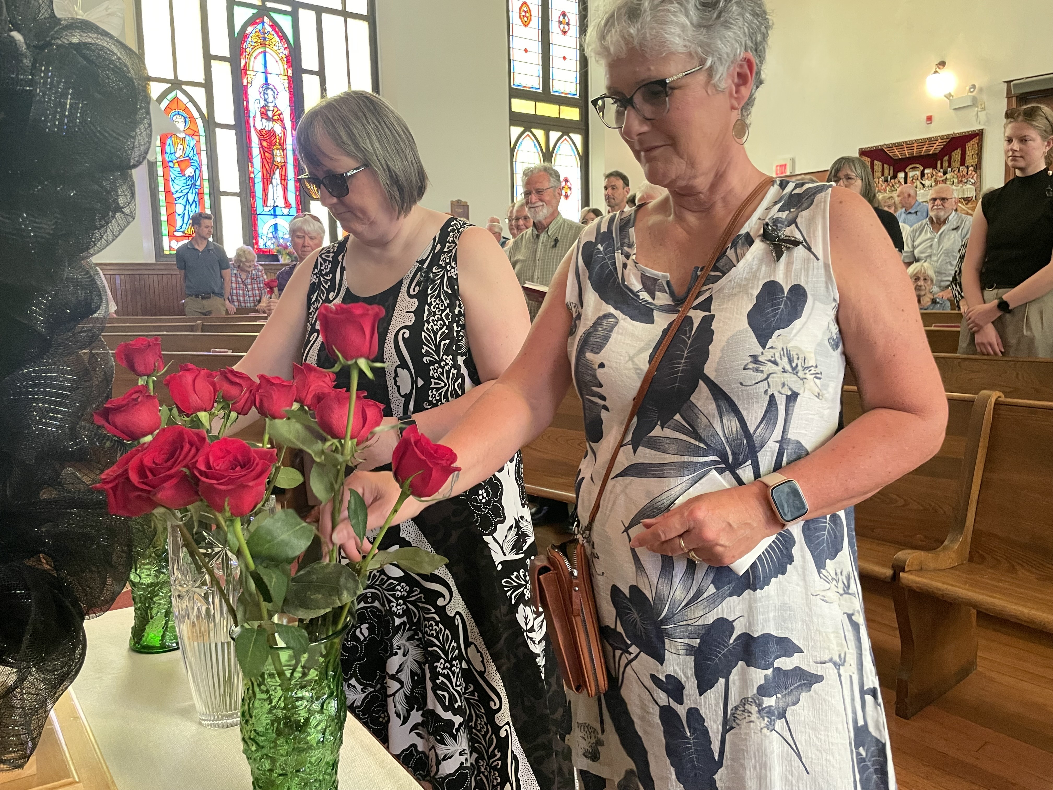 Two women place red roses in vases at the front of St. Andrew's Wesley United Church in Springhill during Miners' Memorial Day on Thursday, June 11, 2026
